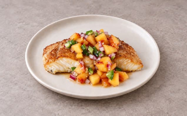 A serving of soy ginger glazed halibut with ginger peach relish on a plain white dish